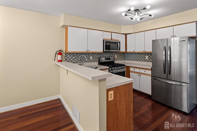 204 Concord Pl, North Brunswick, NJ 08902 - kitchen featuring stainless steel appliances, a peninsula, light countertops, backsplash, and dark wood-style flooring