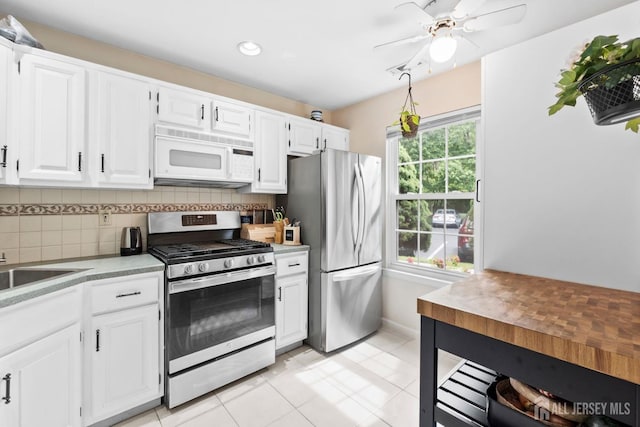 372 Mcdowell Dr, East Brunswick, NJ 08816 - kitchen featuring appliances with stainless steel finishes, backsplash, light countertops, ceiling fan, and white cabinets