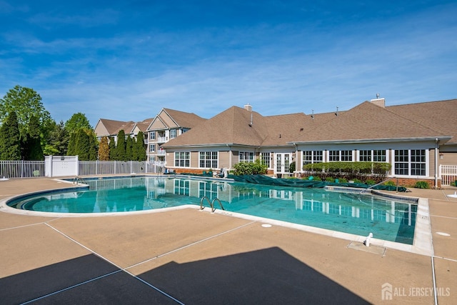 community pool with fence and a patio area