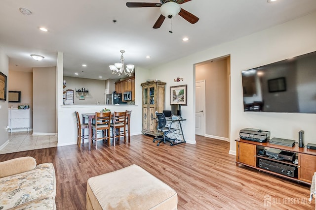 living area with light wood-type flooring, recessed lighting, baseboards, and ceiling fan with notable chandelier