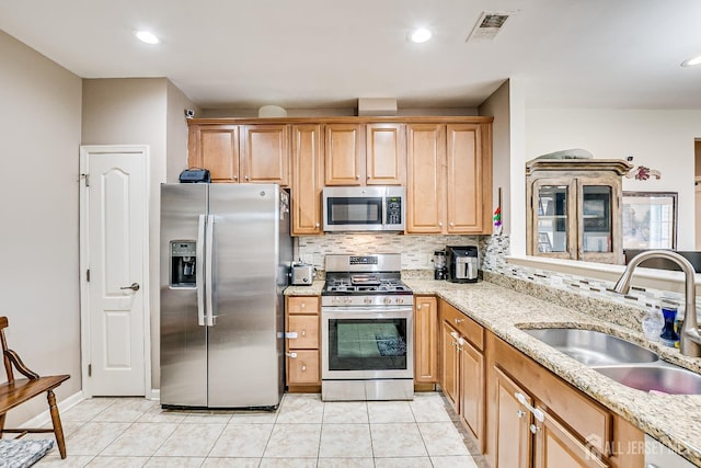 kitchen with visible vents, a sink, backsplash, light tile patterned floors, and stainless steel appliances