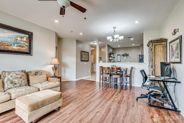 living room with visible vents, baseboards, recessed lighting, light wood-style flooring, and ceiling fan with notable chandelier