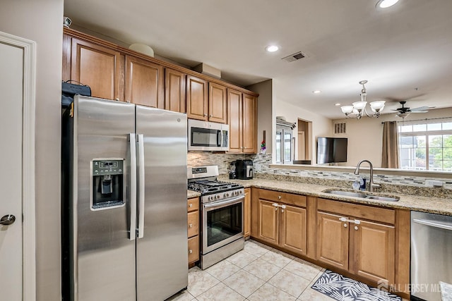 kitchen featuring appliances with stainless steel finishes, brown cabinetry, a sink, and visible vents