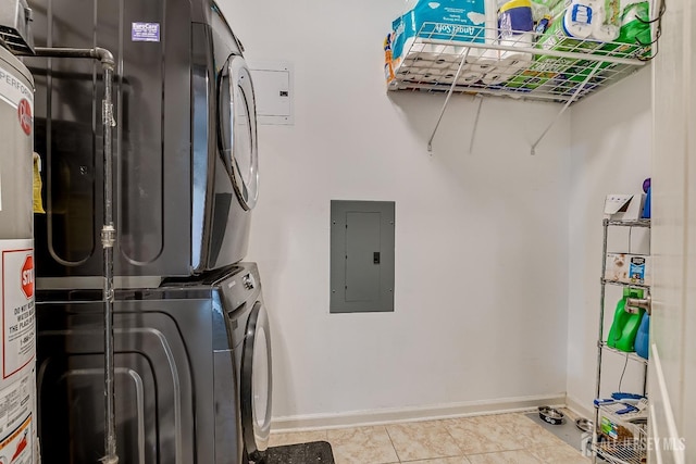 laundry area with laundry area, electric panel, stacked washer and dryer, baseboards, and light tile patterned flooring