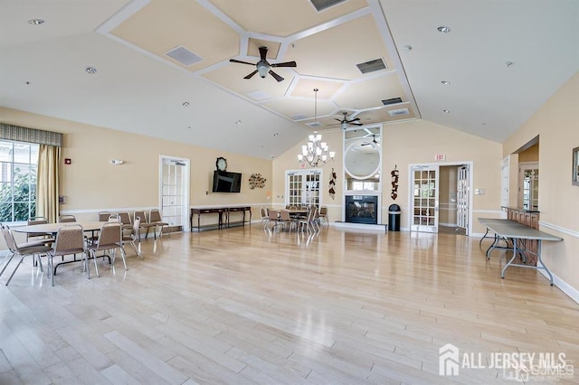 living area with visible vents, high vaulted ceiling, baseboards, ceiling fan with notable chandelier, and light wood-style floors