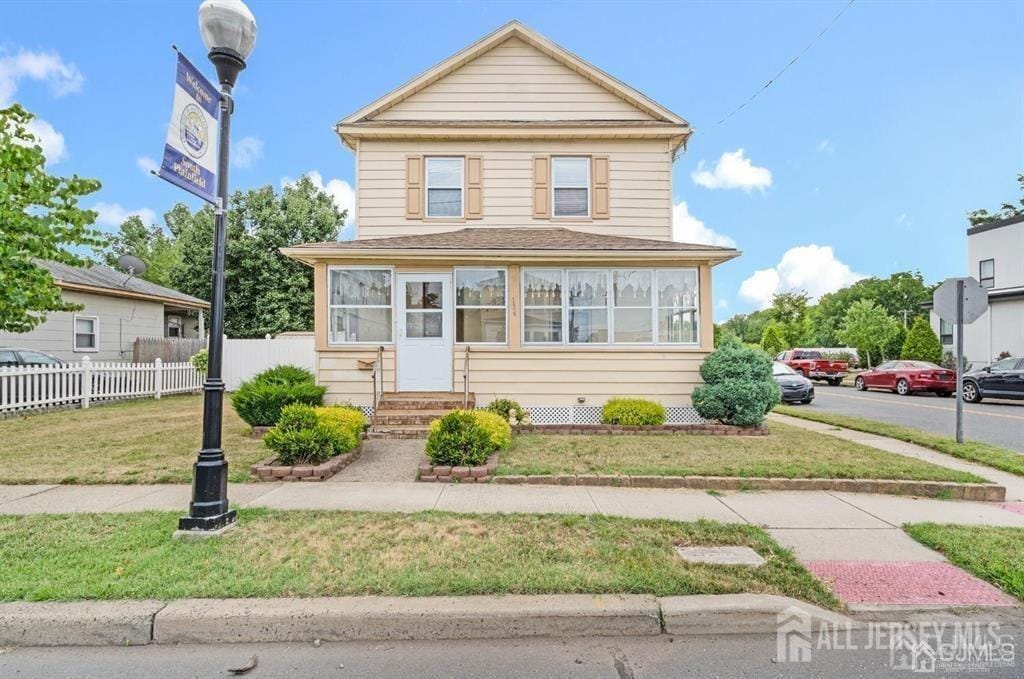 view of front of house with a sunroom, fence, a front yard, and entry steps