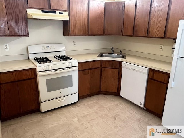 kitchen with white appliances, under cabinet range hood, light countertops, and a sink