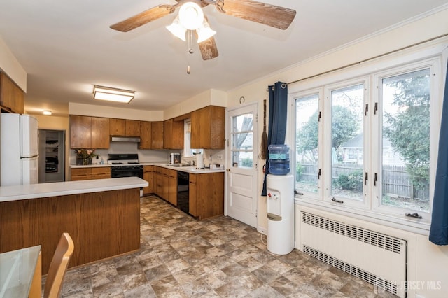 kitchen featuring radiator, brown cabinets, freestanding refrigerator, black dishwasher, and a sink