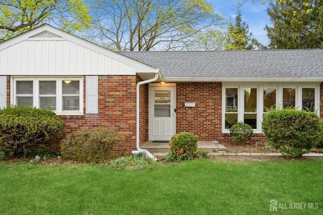 ranch-style house with brick siding, a front lawn, and a shingled roof