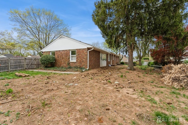 view of home's exterior featuring brick siding and fence
