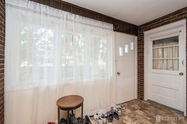 foyer entrance featuring brick wall and stone finish floors