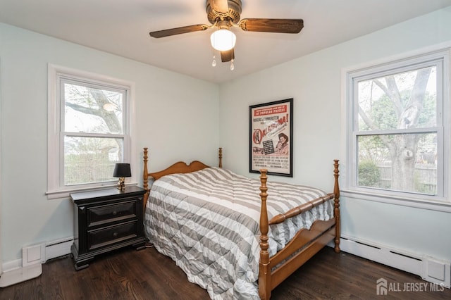 bedroom with a baseboard heating unit, dark wood-style floors, and ceiling fan