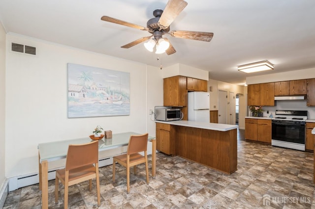 kitchen with range with gas stovetop, stainless steel microwave, freestanding refrigerator, a peninsula, and brown cabinets