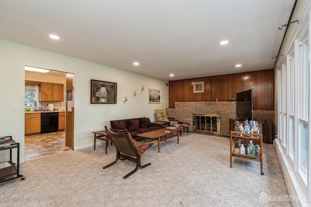 living room featuring recessed lighting, light colored carpet, wooden walls, a brick fireplace, and baseboards