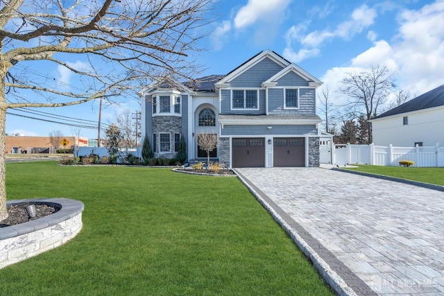 view of front facade featuring fence, a front lawn, a garage, stone siding, and decorative driveway