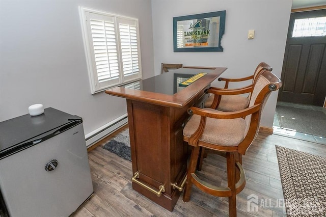 bar area with a baseboard radiator, light wood-style flooring, and baseboards