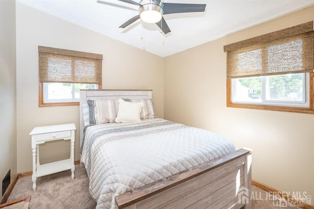 bedroom featuring multiple windows, baseboards, light carpet, and ceiling fan