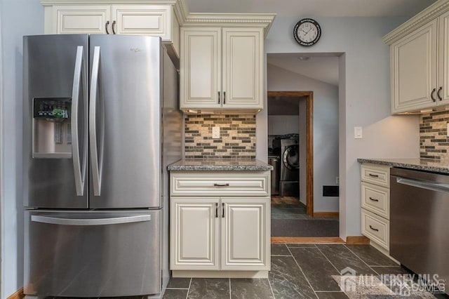 kitchen with appliances with stainless steel finishes, cream cabinetry, tasteful backsplash, stone counters, and washer / dryer