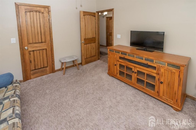 living area featuring light colored carpet and baseboards