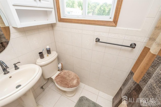 bathroom featuring a sink, tile walls, and toilet