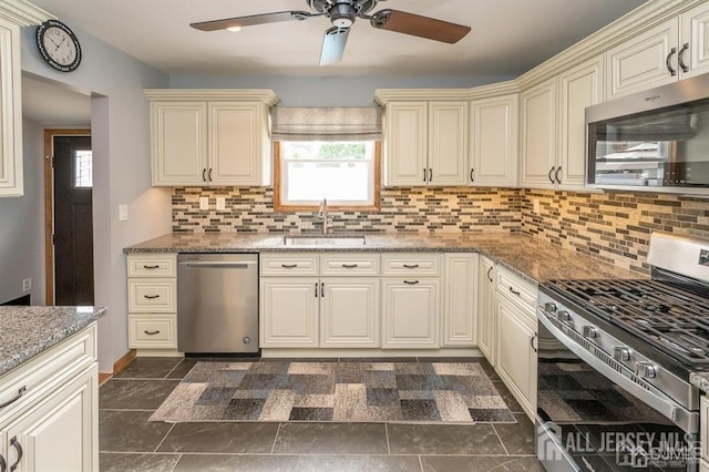 kitchen with appliances with stainless steel finishes, cream cabinets, a sink, and a ceiling fan