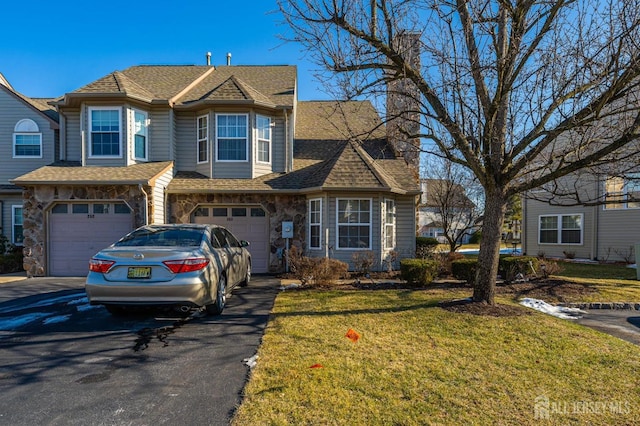 view of front of property featuring aphalt driveway, stone siding, a front yard, a shingled roof, and a garage