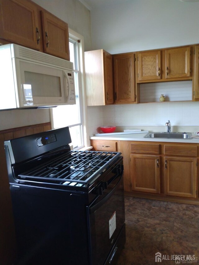 kitchen featuring black gas range oven, sink, and decorative backsplash