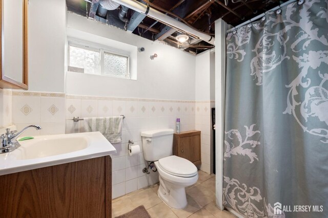 bathroom featuring tile patterned floors, toilet, sink, and tile walls