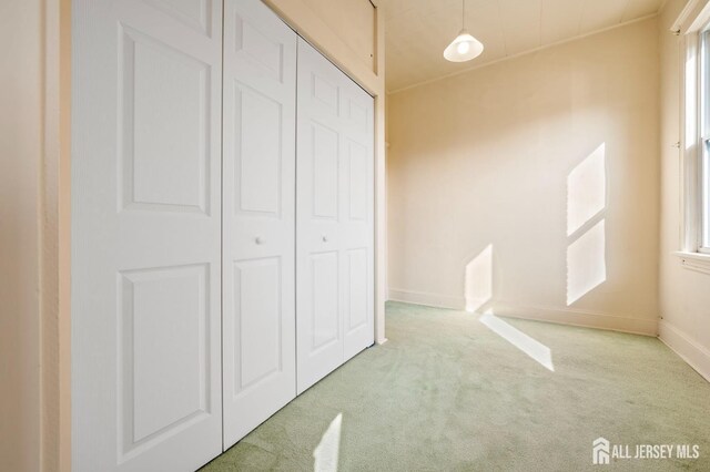 unfurnished bedroom featuring multiple windows, light carpet, and a closet