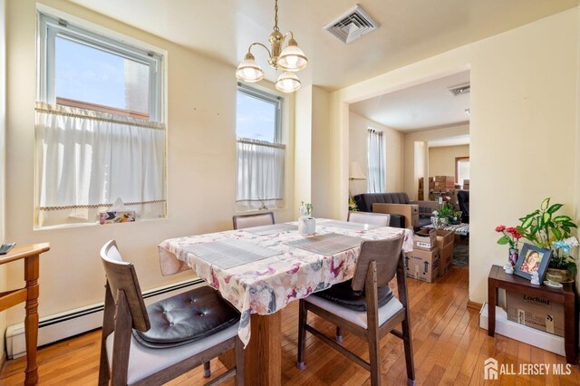 dining room featuring a chandelier, baseboard heating, and light hardwood / wood-style flooring