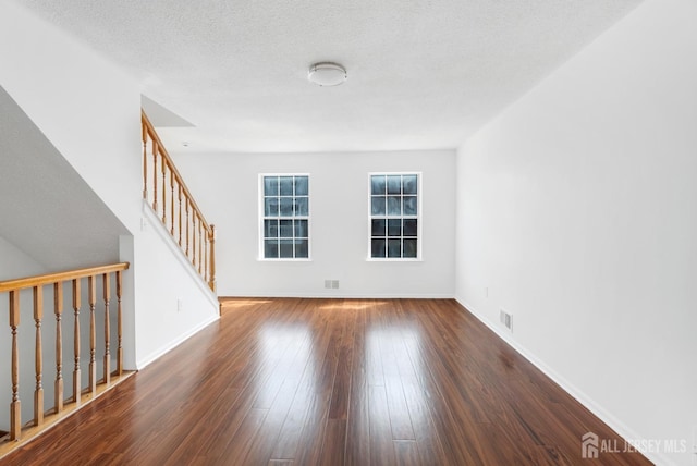 spare room featuring visible vents, baseboards, a textured ceiling, and wood finished floors