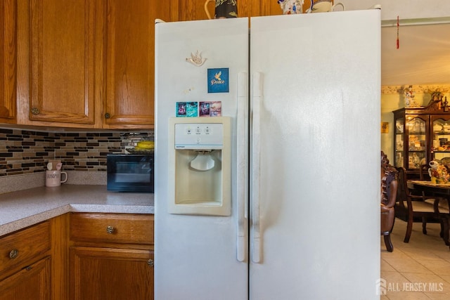 99 William St, South River, NJ 08882 - kitchen with white refrigerator with ice dispenser, light tile patterned floors, tasteful backsplash, brown cabinets, and light countertops