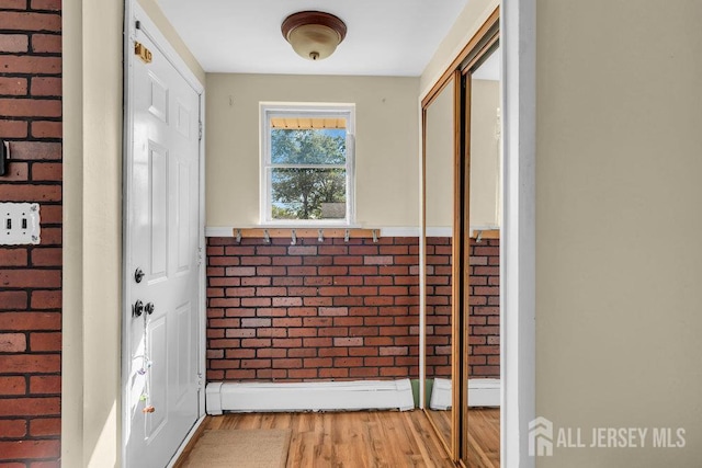 73 Webb Dr, Fords, NJ 08863 - doorway featuring light wood finished floors, brick wall, and baseboard heating