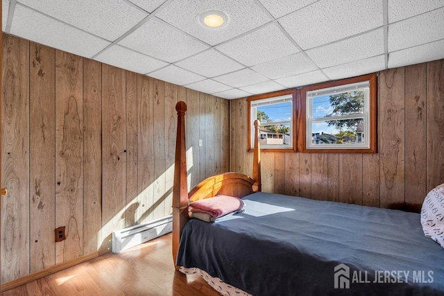73 Webb Dr, Fords, NJ 08863 - bedroom featuring baseboard heating, wooden walls, wood finished floors, and a paneled ceiling