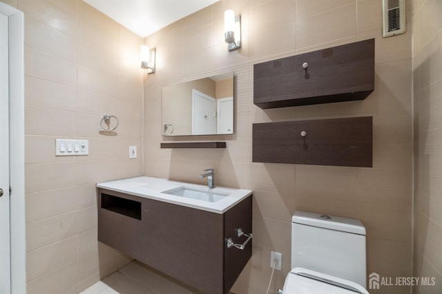 bathroom featuring vanity, tile walls, toilet, and visible vents