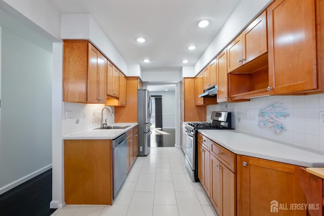 kitchen featuring a sink, under cabinet range hood, stainless steel appliances, brown cabinetry, and light countertops