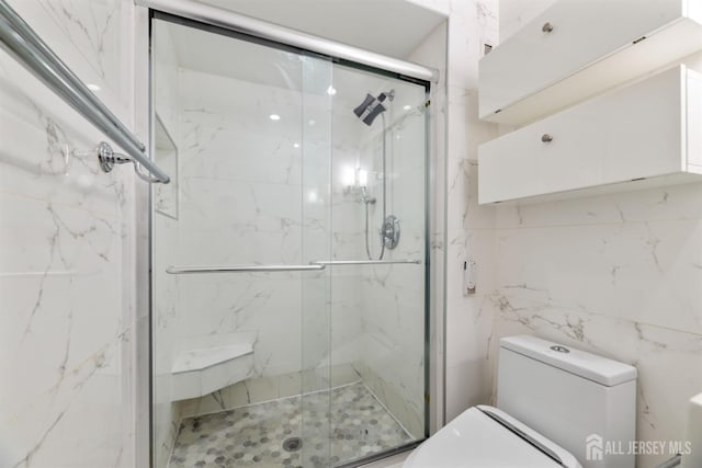 bathroom featuring toilet and a marble finish shower