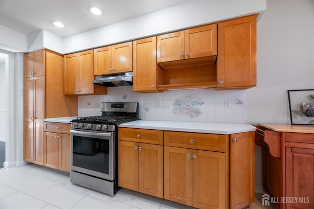 kitchen with light countertops, tasteful backsplash, stainless steel gas stove, and under cabinet range hood