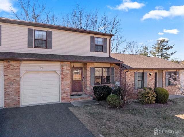 view of front of property with brick siding, an attached garage, a shingled roof, and driveway