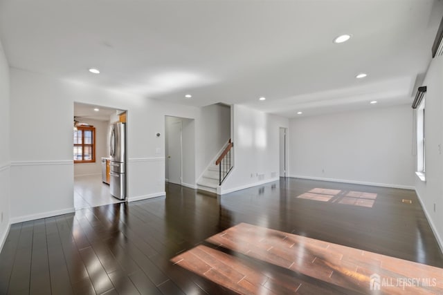 unfurnished room featuring recessed lighting, baseboards, wood finished floors, and stairs