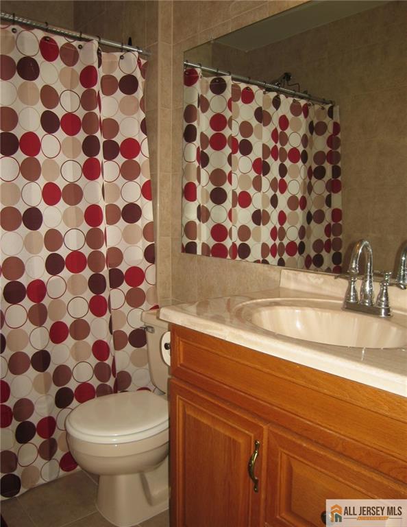 bathroom with toilet, tile patterned floors, and vanity