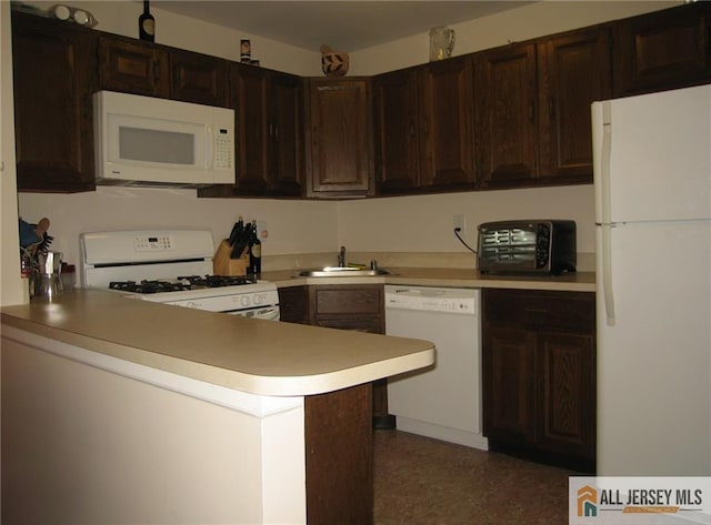 kitchen featuring sink, white appliances, dark brown cabinets, and kitchen peninsula