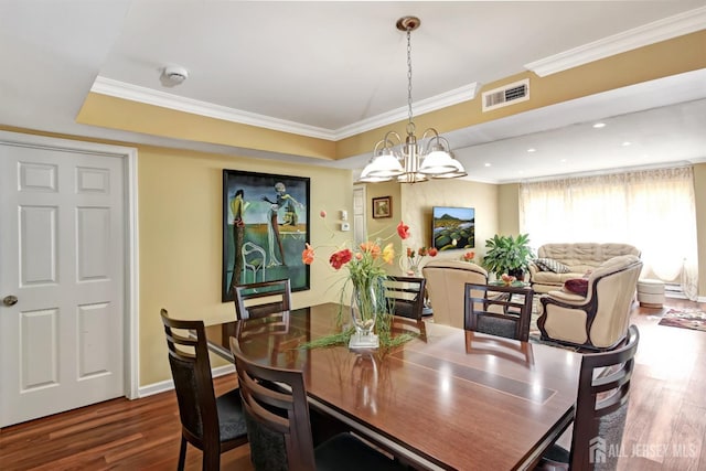 dining area featuring hardwood / wood-style floors, crown molding, and a notable chandelier