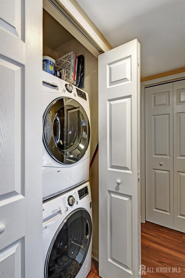 clothes washing area featuring stacked washer / drying machine and dark hardwood / wood-style floors