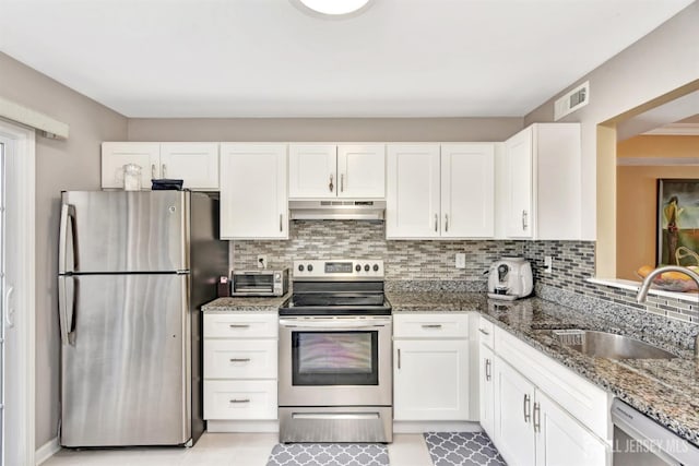 kitchen with white cabinetry, sink, decorative backsplash, dark stone counters, and stainless steel appliances