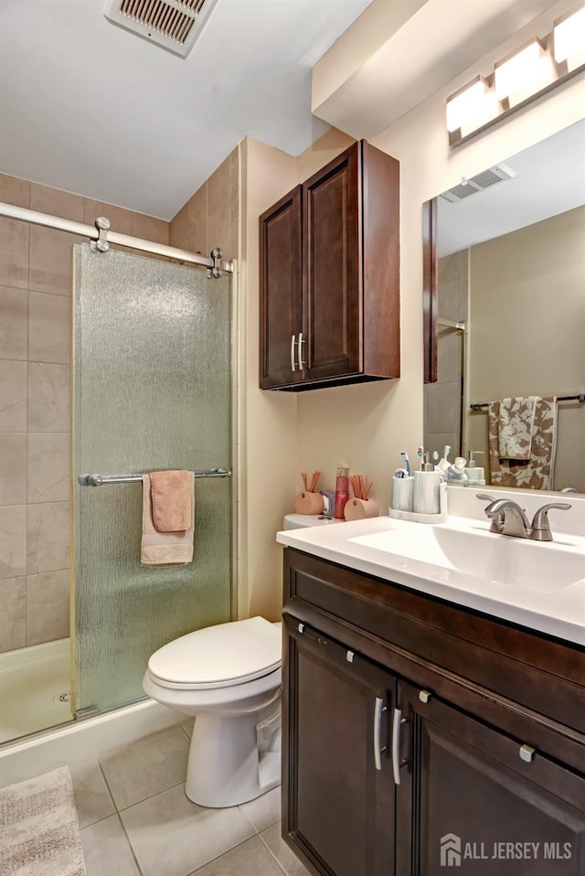 bathroom featuring tile patterned floors, toilet, a shower with door, and vanity