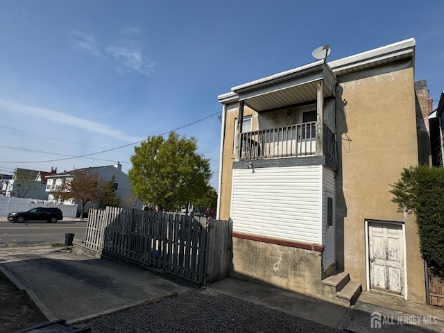 134 S Stevens Ave S, South Amboy, NJ 08879 - view of side of home with fence, stucco siding, a balcony, and entry steps
