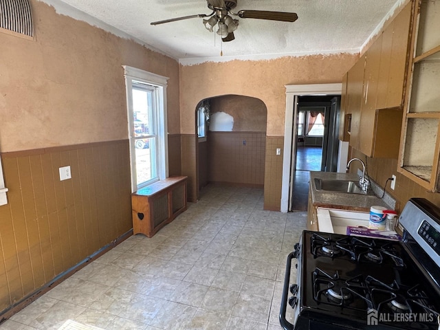 134 S Stevens Ave S, South Amboy, NJ 08879 - kitchen featuring stainless steel gas range oven, a wainscoted wall, a sink, arched walkways, and ceiling fan