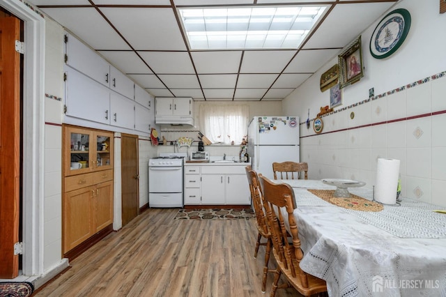 kitchen featuring white cabinetry, sink, white appliances, a drop ceiling, and light wood-type flooring