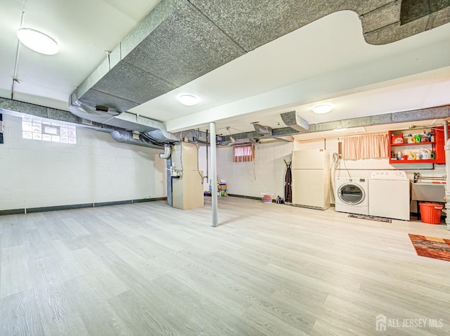 basement featuring separate washer and dryer, sink, light hardwood / wood-style flooring, and white refrigerator